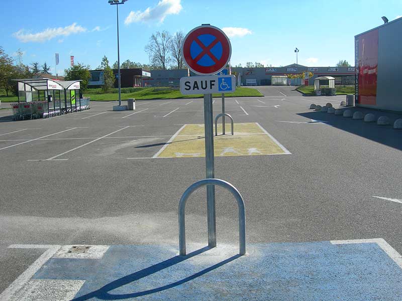 Sur un parking, un panneau de signalisation interdit de stationner sauf pour les handicapés.